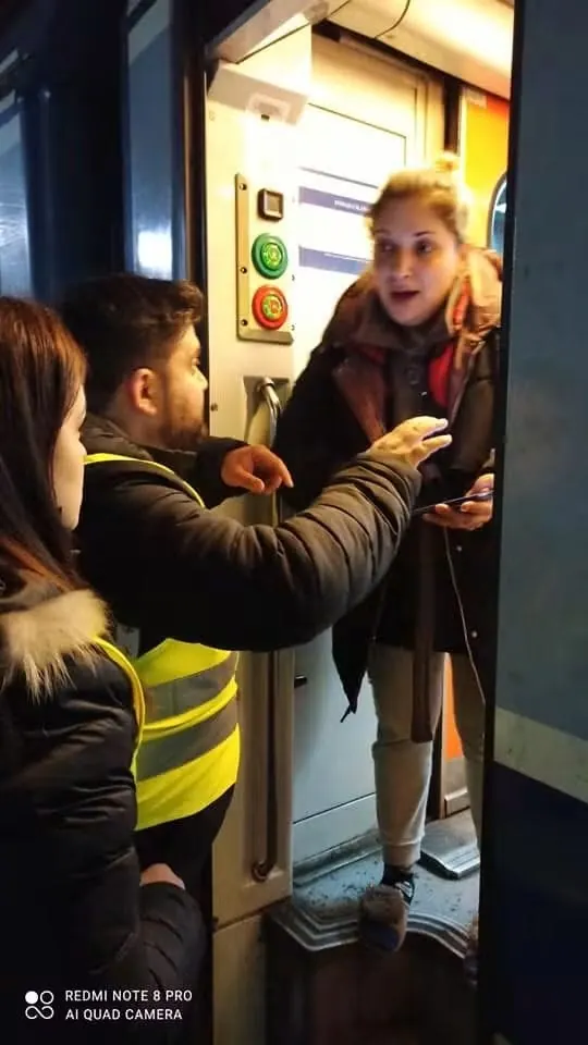 Volunteers guiding a person at the door of a train