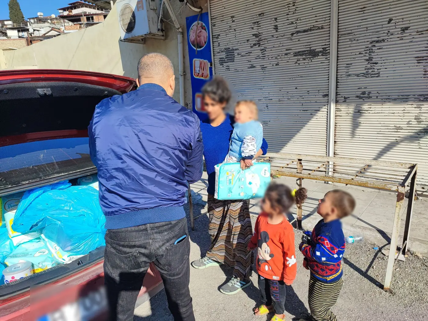 A team member handing nappies to a family, faces hidden